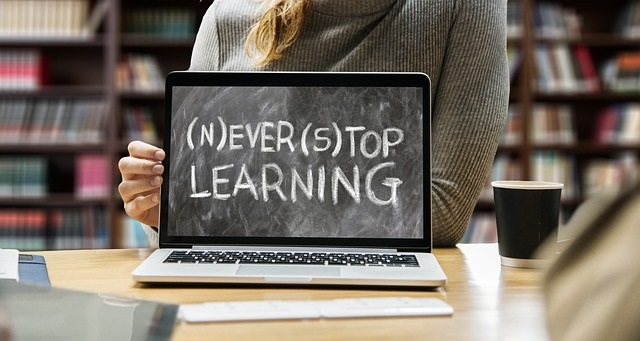 A laptop on a desk with the words 'Never stop learning' on the screen.
